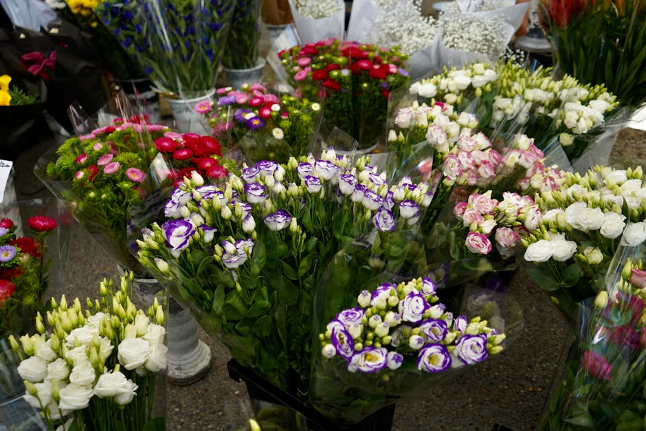 A vibrant display of fresh floral bouquets arranged on a table at Walthamstow Market stalls, showcasing a variety of flowers including white eustoma, purple and white irises, pink roses, red and pink 